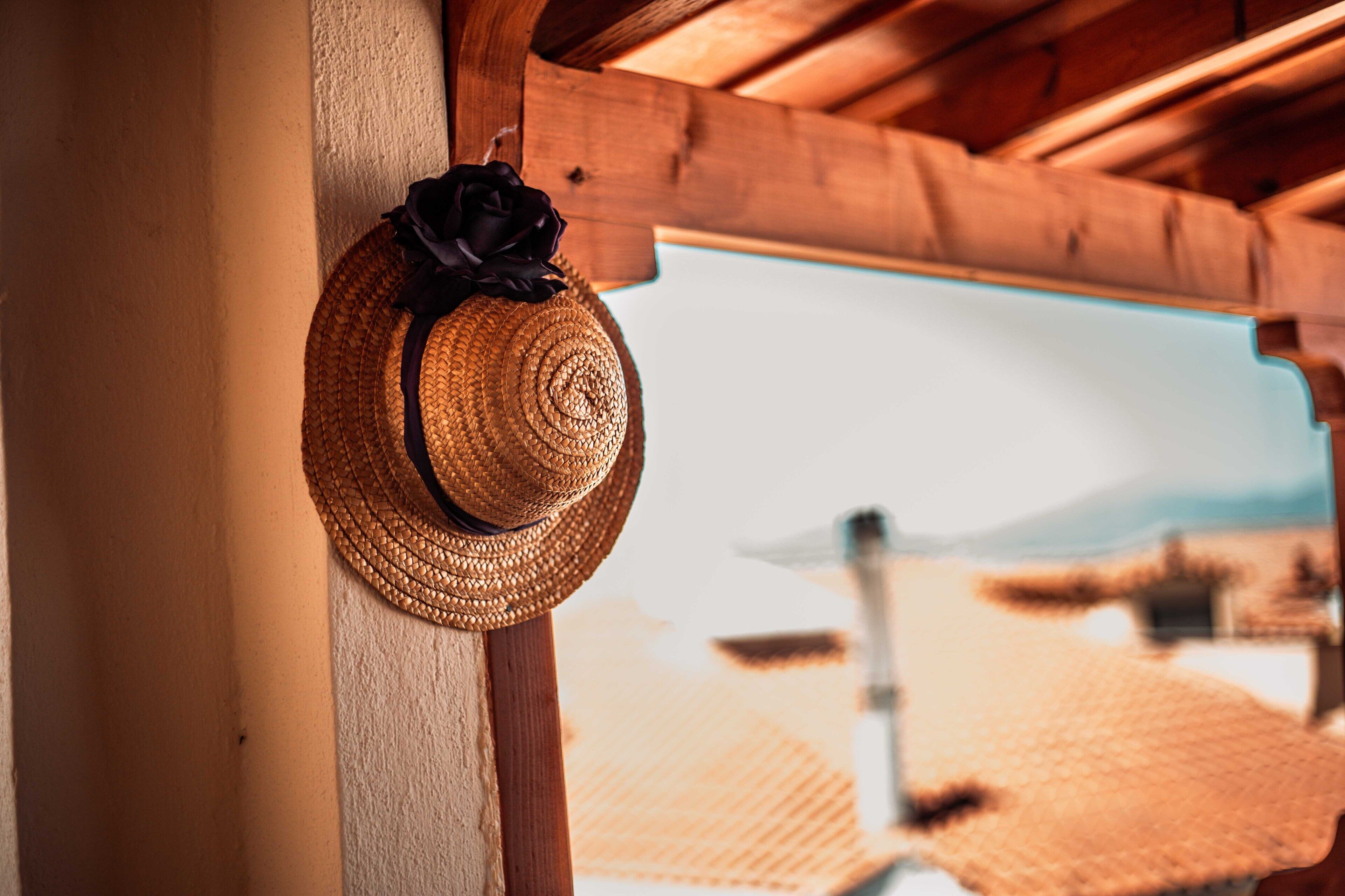 Un cappello di paglia con un nastro nero appeso a una trave di legno.
