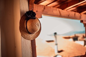 A straw hat with a black ribbon hanging on a wooden beam.