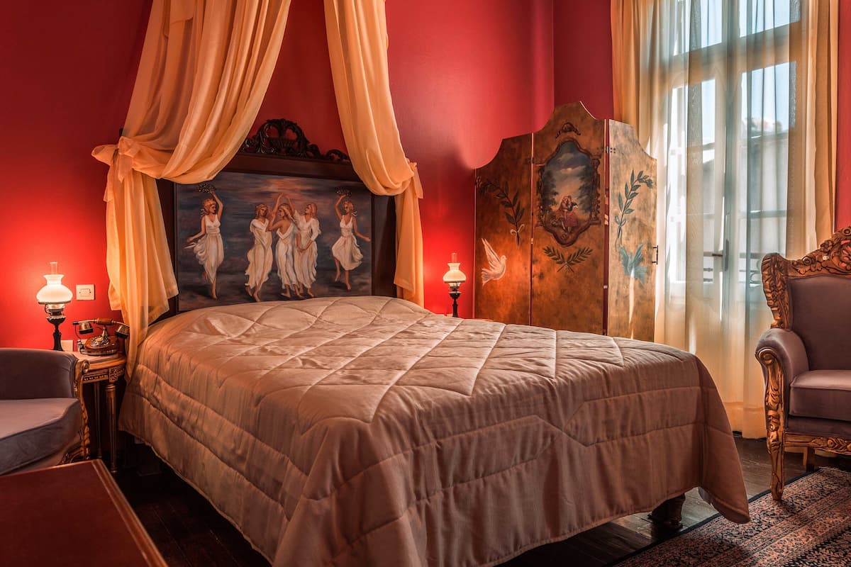 Una cama con dosel, un cuadro en la cabecera, una silla y una lámpara.