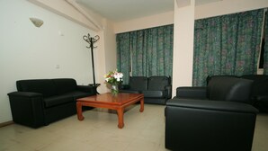 A living room with two black sofas, a wooden coffee table, and a floor lamp. - Alma Hotel (Athens)