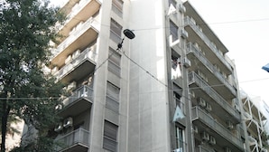 A multi-story building with balconies, outdoor seating, and a red umbrella. - Alma Hotel (Athens)