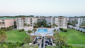 A hotel with a central pool, surrounded by lush greenery and palm trees. - Hodnett Cooper's Beach Club (St. Simons Island)