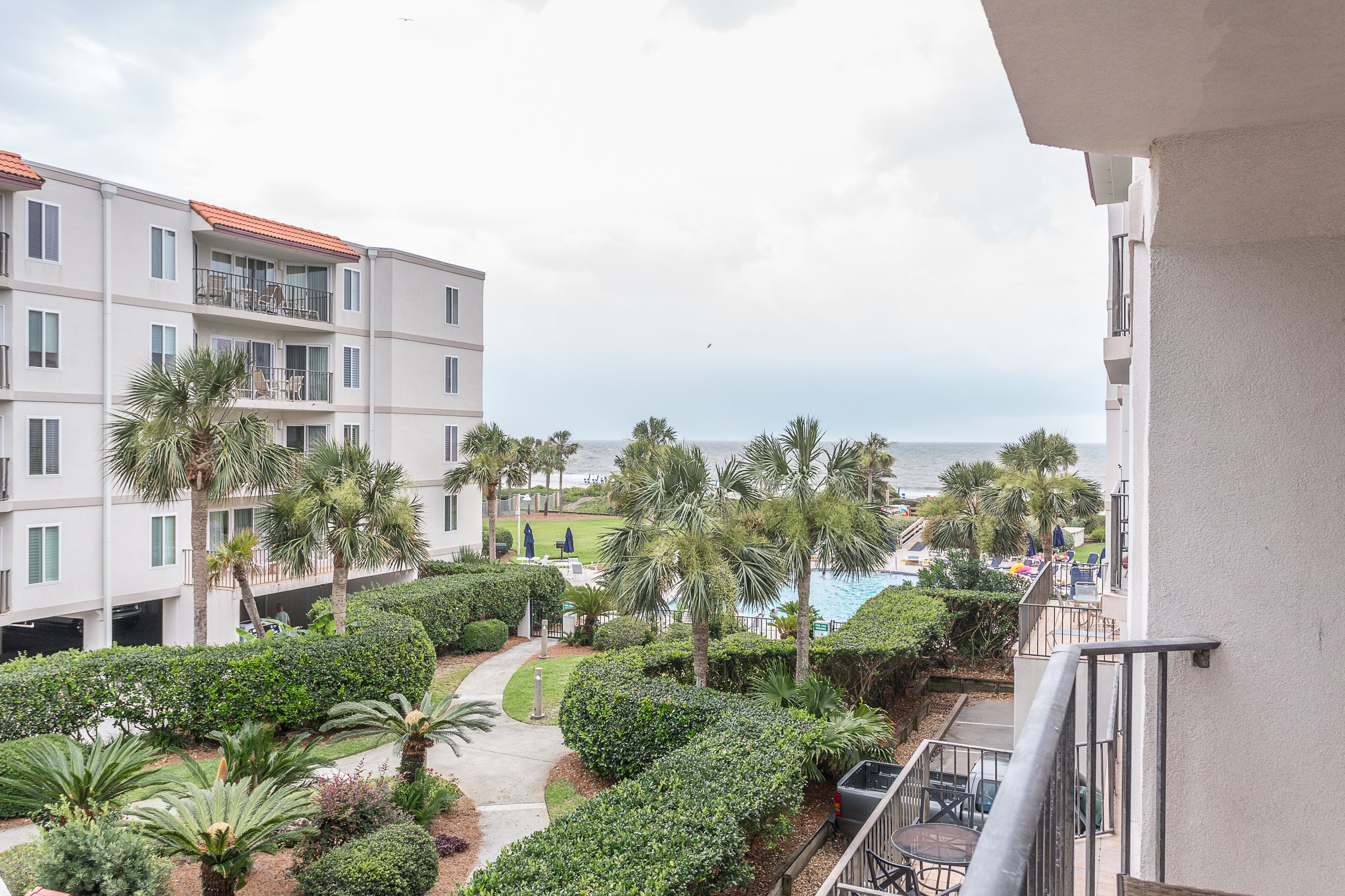 A residential building with balconies, a swimming pool, and a view of the sea.