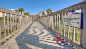 A wooden boardwalk leading to a building with a sign indicating it is private property for residents and guests only. - Hodnett Cooper's Beach Club (St. Simons Island)