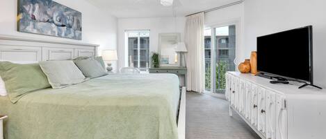 Ein Schlafzimmer mit Bett, Fernseher, Deckenventilator und einem Balkon mit Blick.