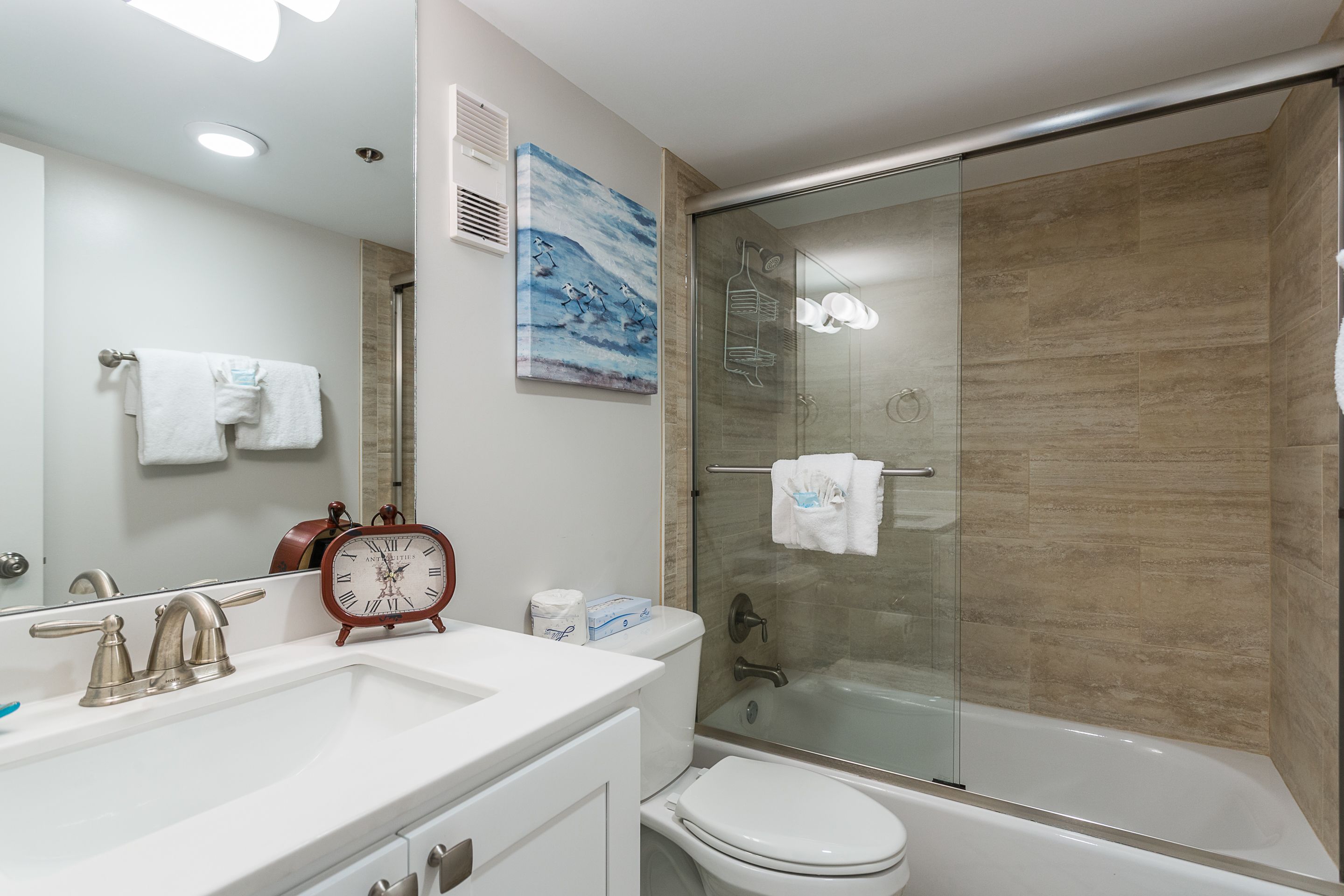 A bathroom with a sink, toilet, and glass-enclosed shower.