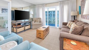 A spacious living room with a flat-screen TV, a wooden chest, and a sofa set. - Hodnett Cooper's Beach Club (St. Simons Island)