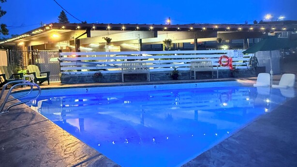 A swimming pool with a clear view of the poolside area, including lounge chairs and a covered seating area. - Timbers INN and Suites (Ashland)