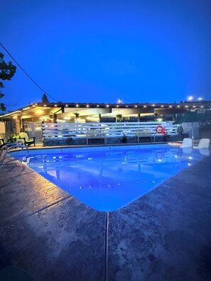 A swimming pool with a clear view of the poolside area, including lounge chairs and a covered seating area. - Timbers INN and Suites (Ashland)