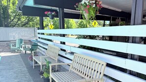 A covered outdoor seating area with benches and potted plants. - Timbers INN and Suites (Ashland)