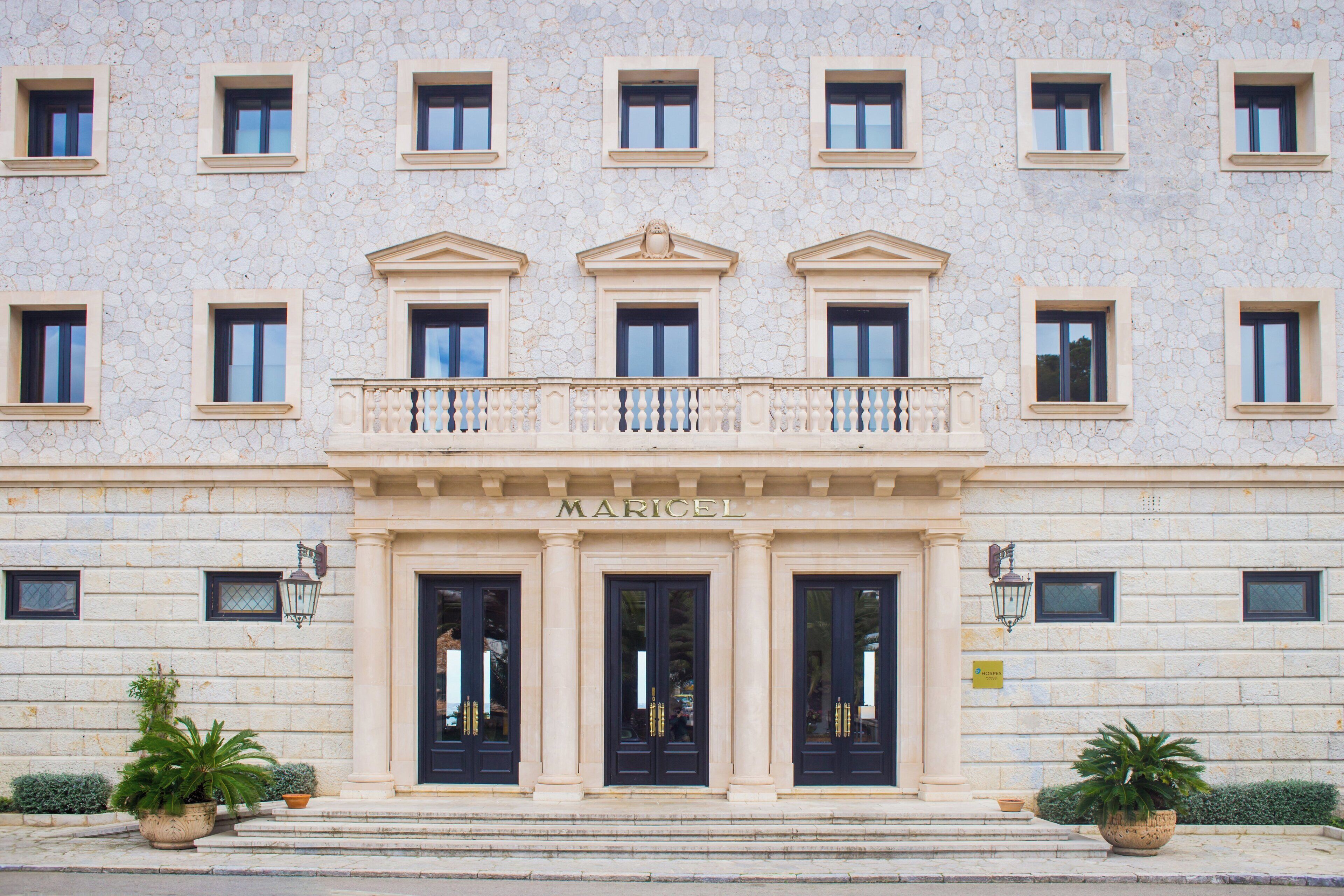 A building with a stone facade, multiple windows, and a central entrance with a balcony.