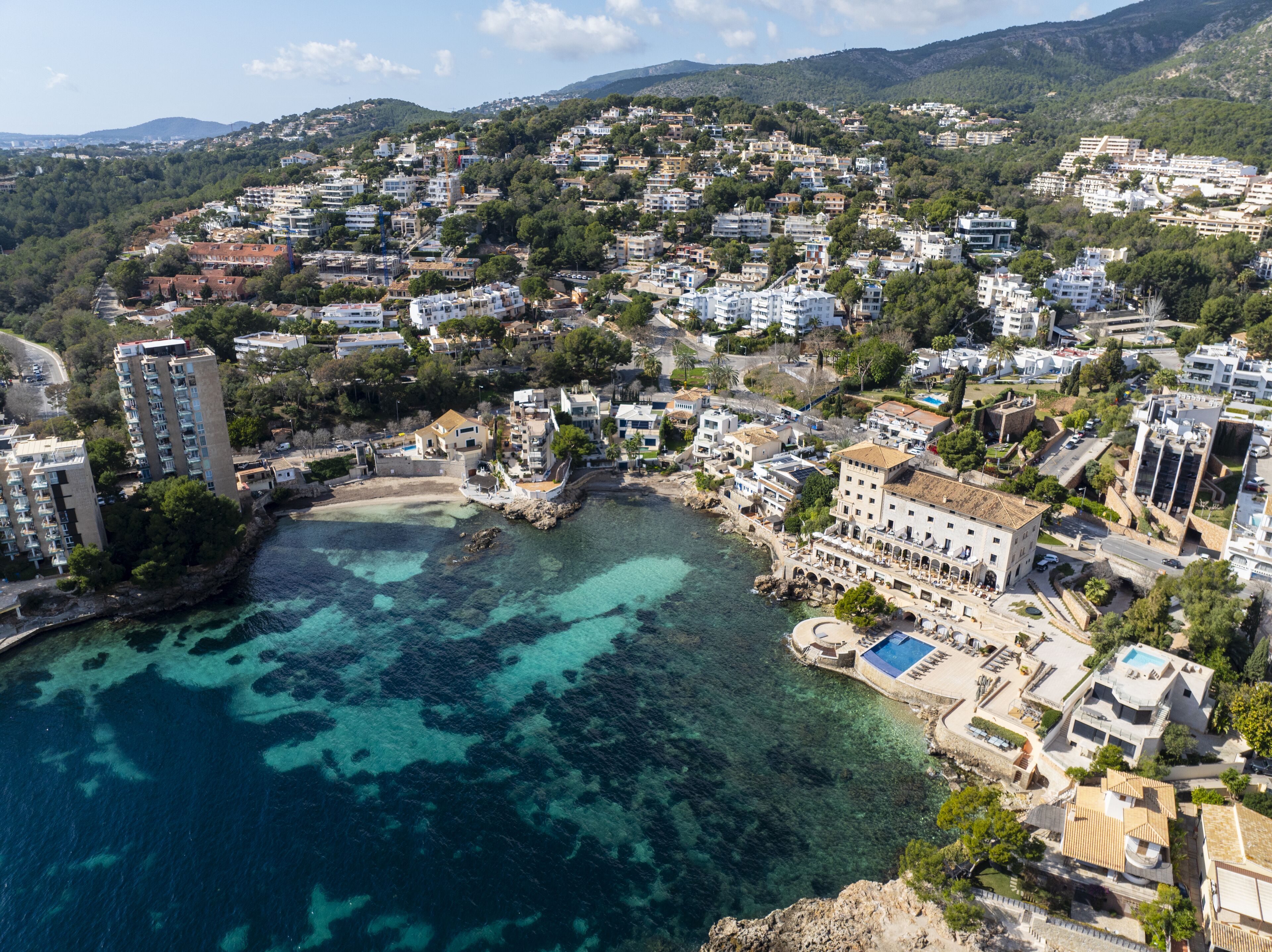 A coastal town with buildings, a beach, and clear blue waters.