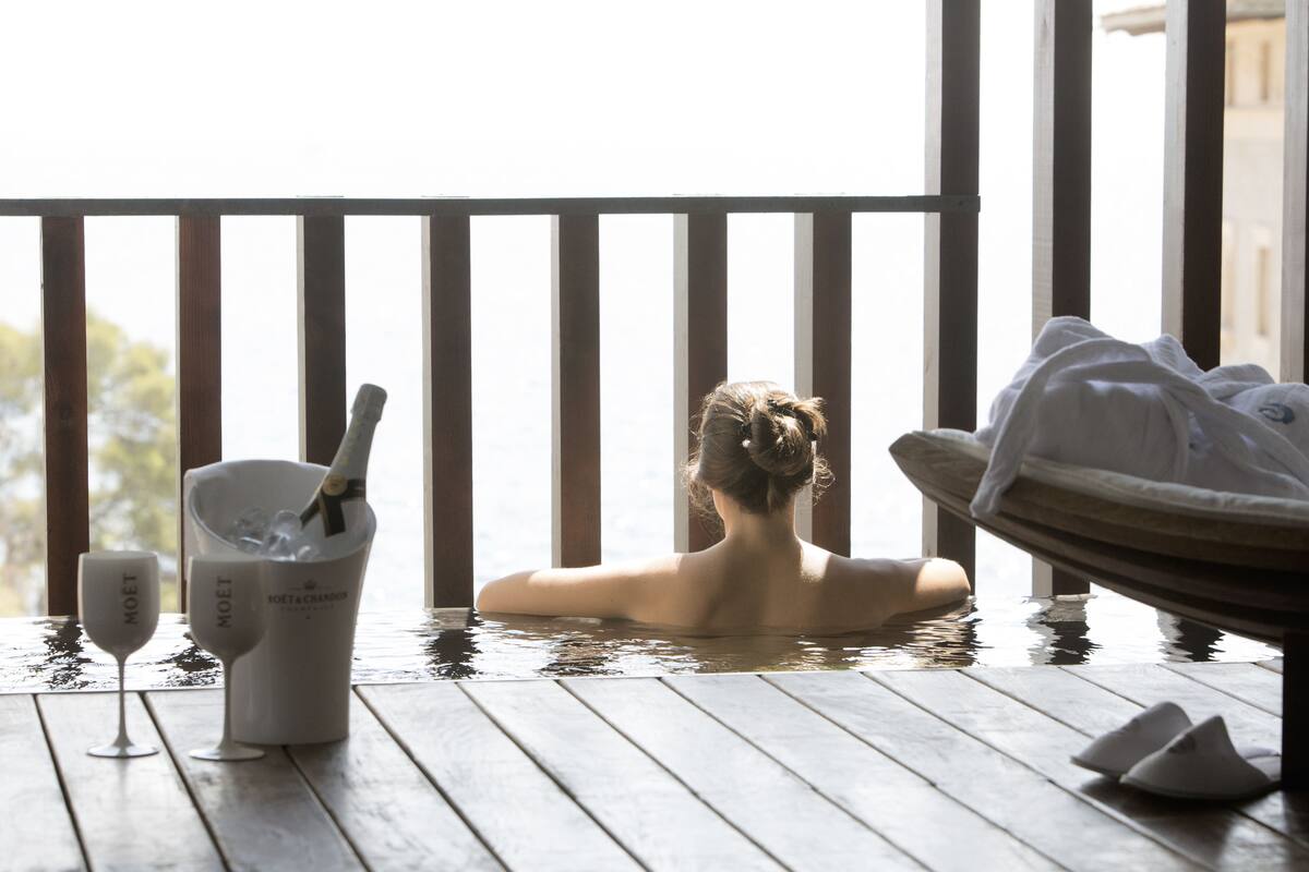 Ein Wellnessbereich mit Holzterrasse, Badewanne und zwei Sektgläsern.