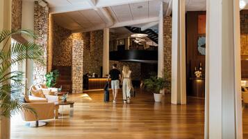 A spacious lobby with a wooden floor, stone walls, and a reception desk.