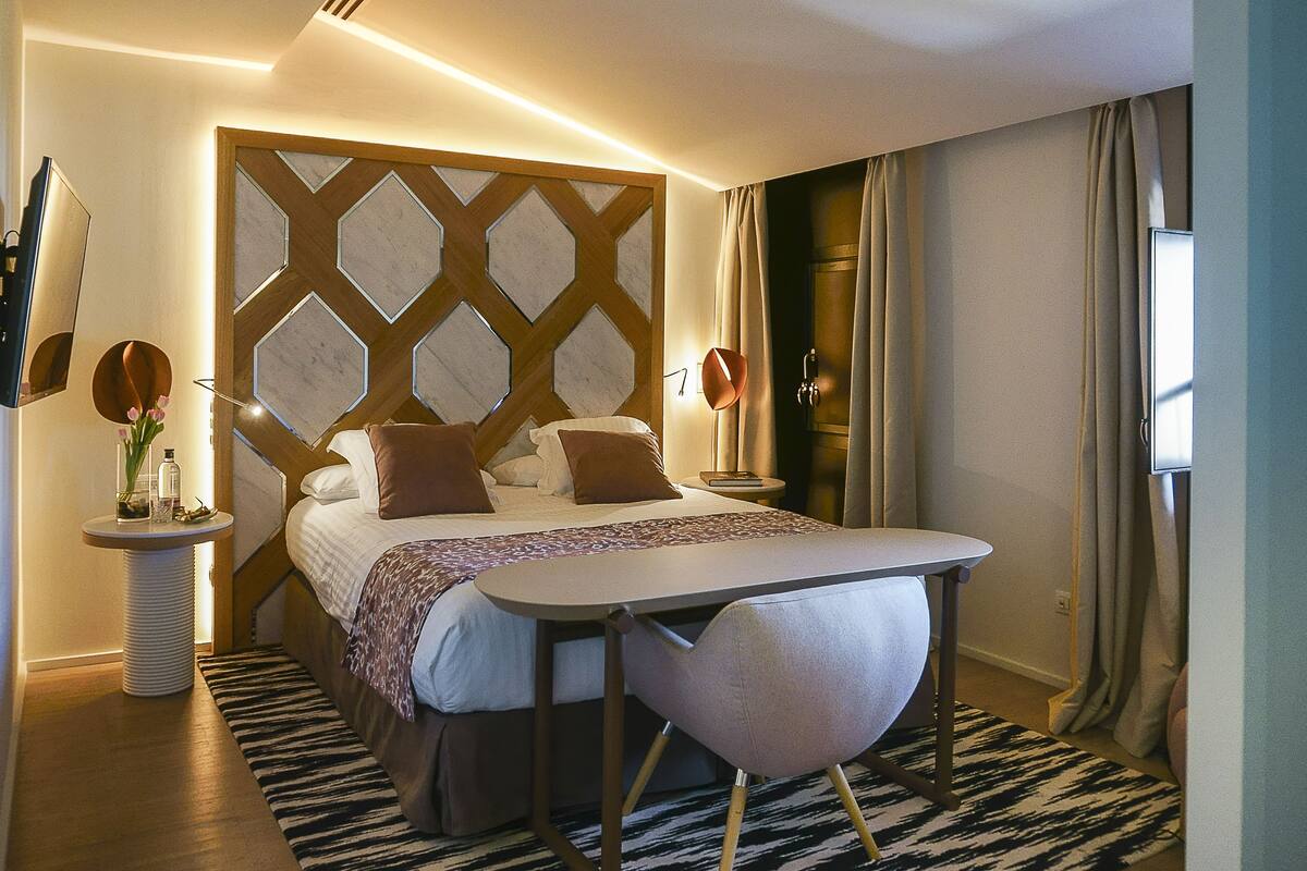 Ein modernes Hotelzimmer mit Bett, Nachttischen, Schreibtisch und Stuhl.