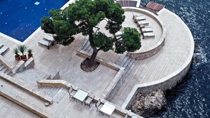 A poolside area with a circular seating arrangement, a tree, and a clear view of the sea. - Hospes Maricel & Spa, Palma de Mallorca, a Member of Design Hotels (Calvia)