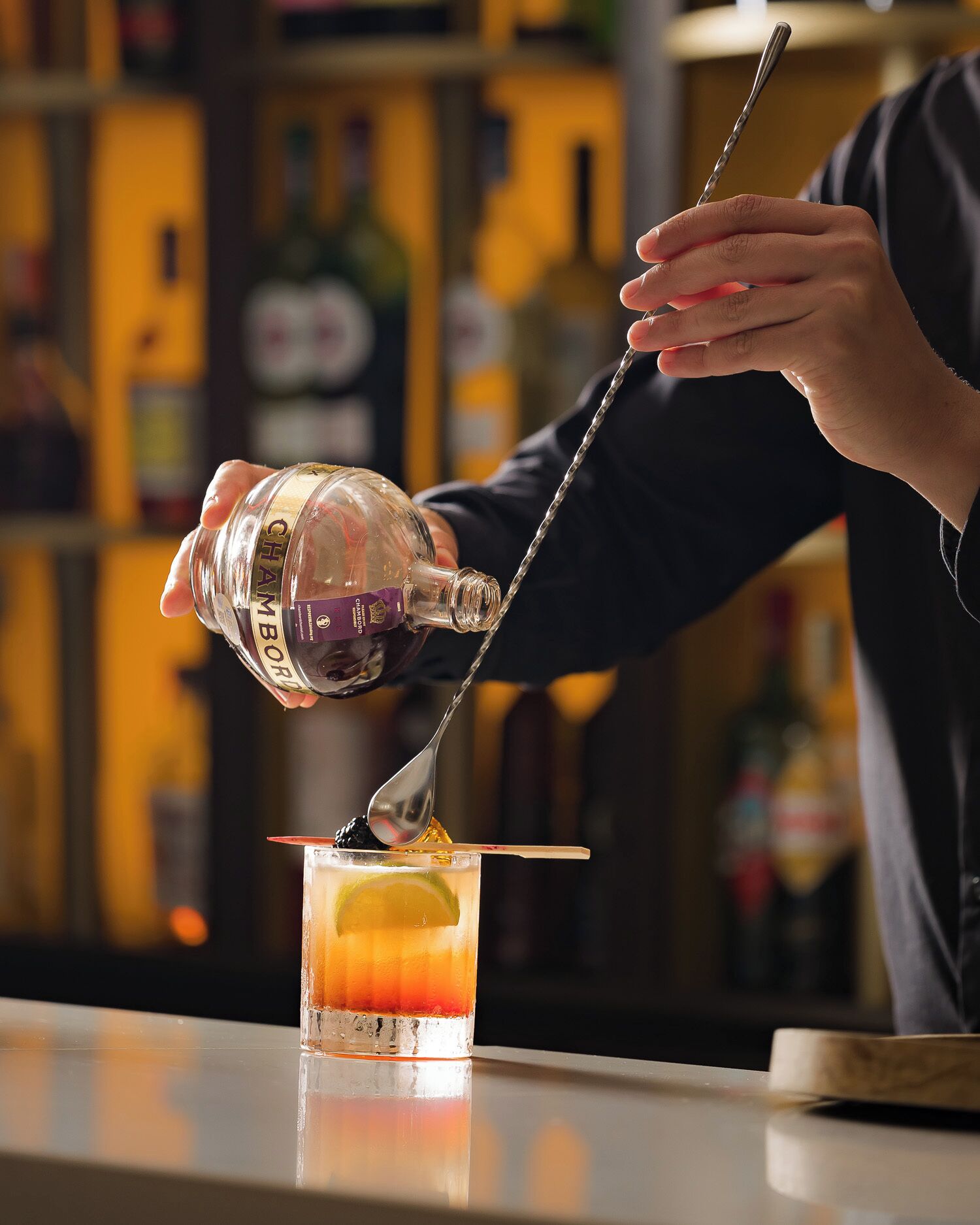 A person pouring a clear liquid into a glass with a straw.