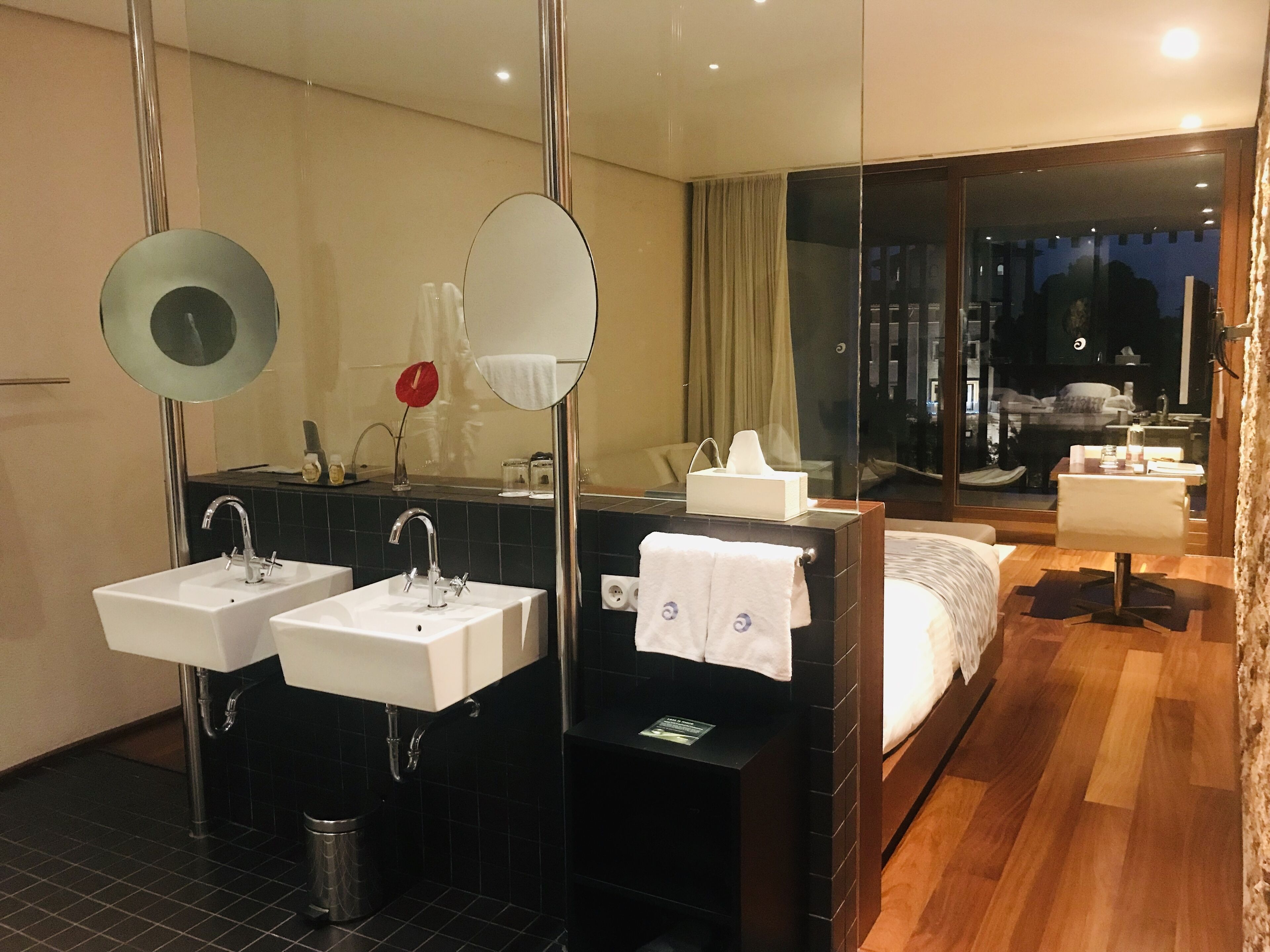 Une salle de bain d’hôtel moderne, dotée de deux lavabos, d’un grand miroir et d’une douche en verre.