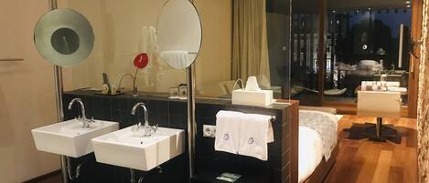 A modern hotel bathroom with two sinks, a large mirror, and a glass shower enclosure.