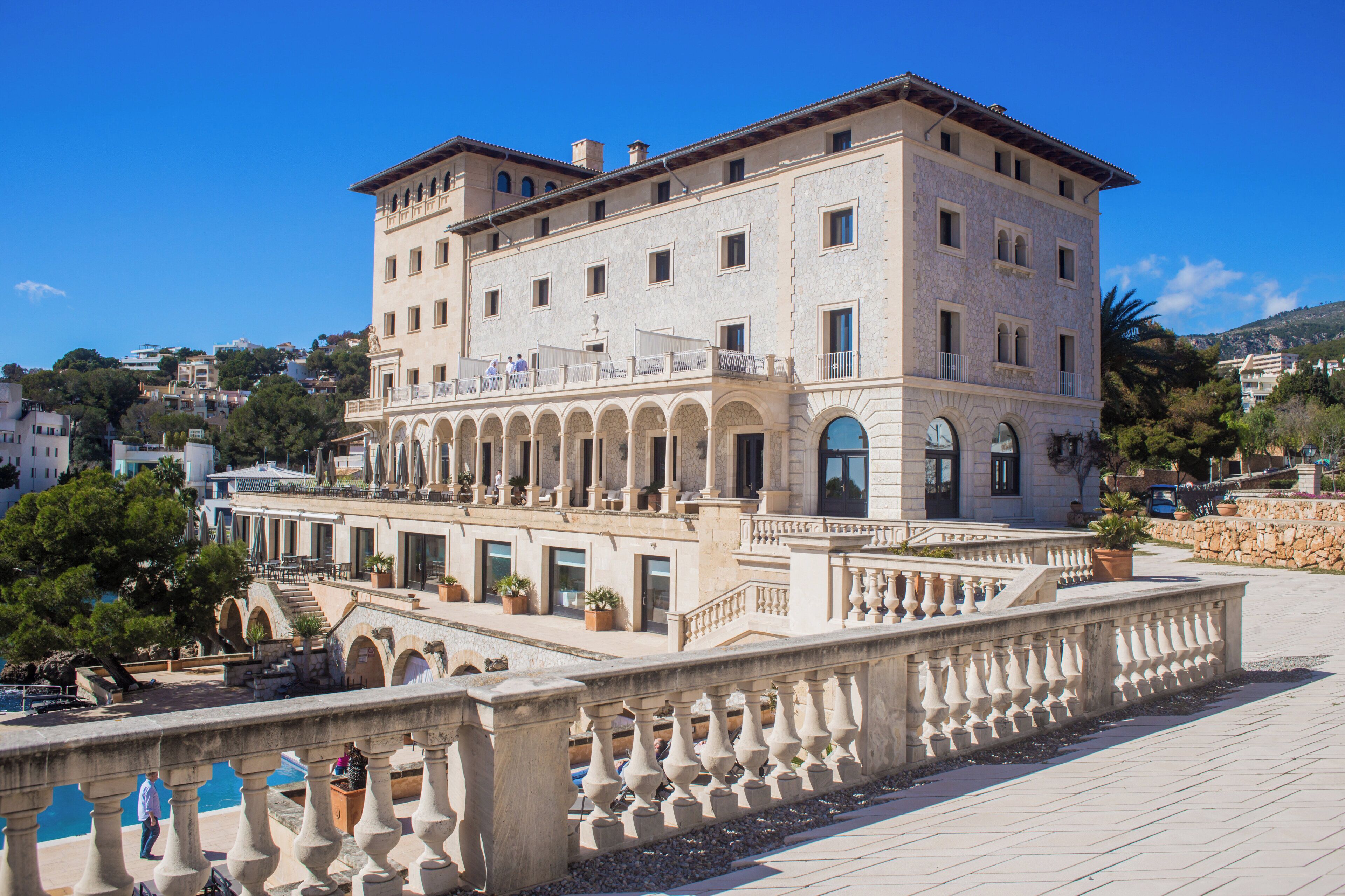 Un edificio grande de varios pisos con un patio central, balcones y una barandilla de piedra.