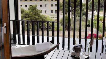A balcony with a wooden floor, a bench, and a small table with a vase and a candle.
