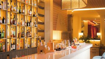 A bar area with shelves of liquor bottles, a counter with bar tools, and a seating area with cushioned chairs.