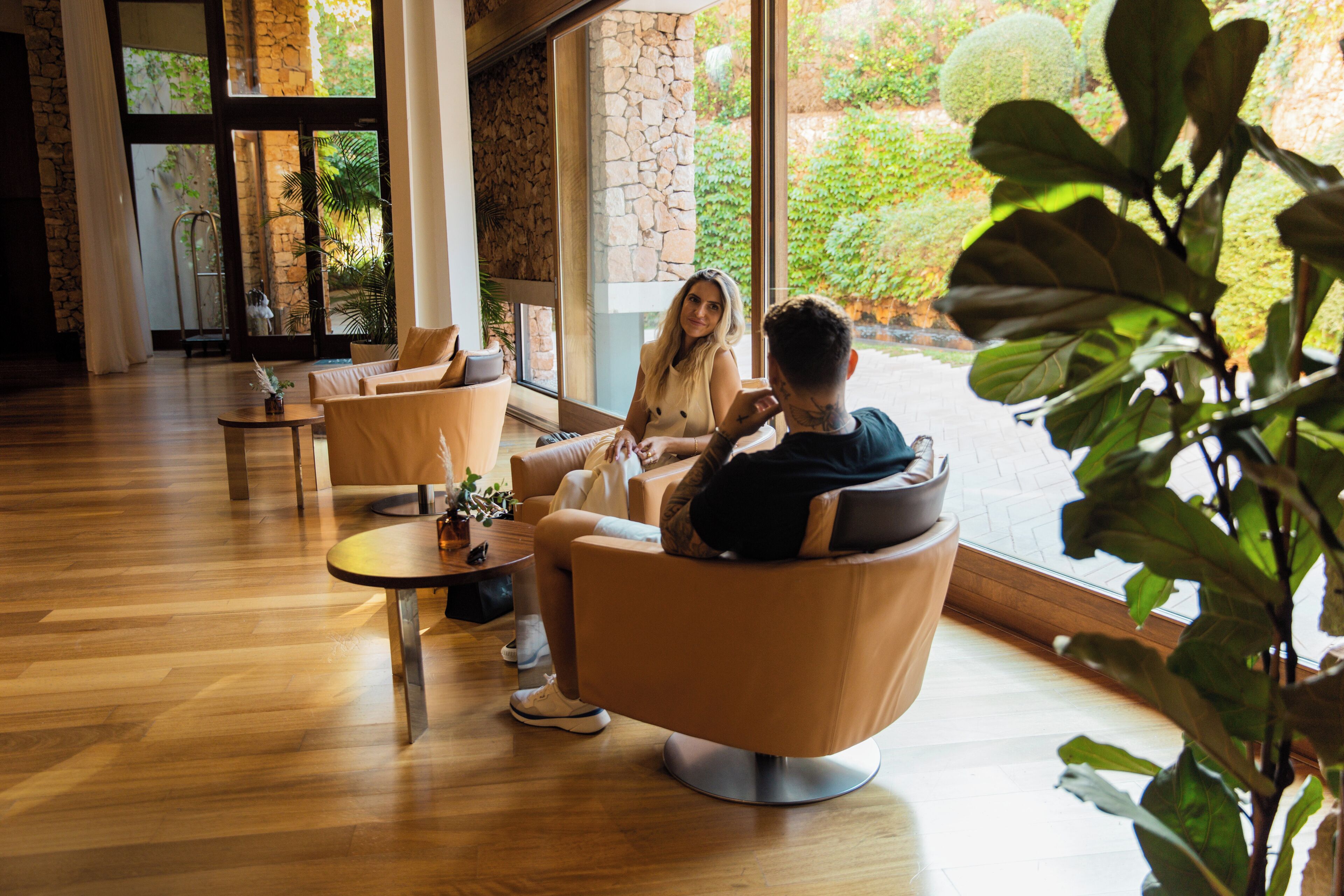 A modern interior with a stone wall, large windows, and a wooden floor.