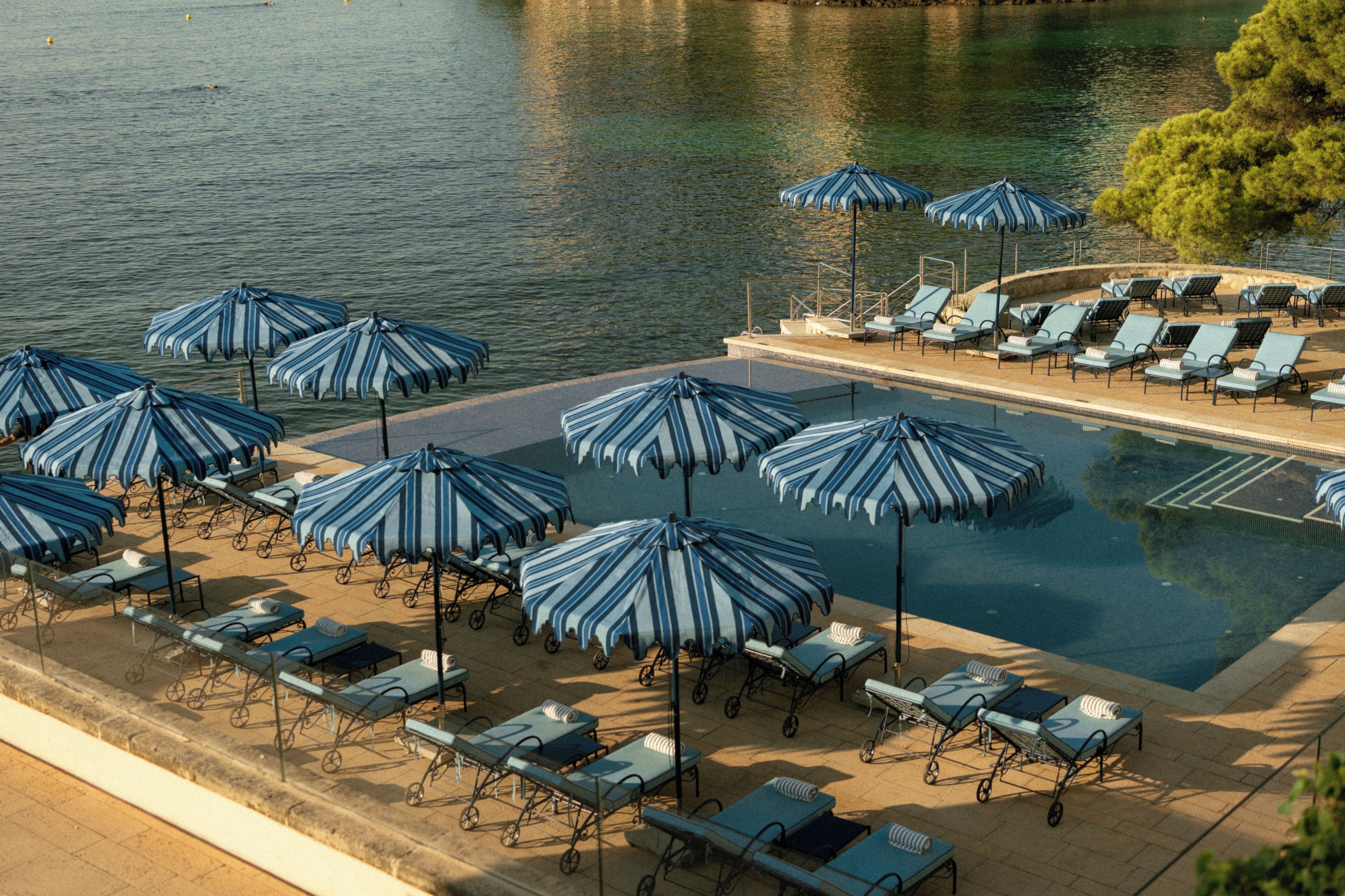A pool area with multiple lounge chairs and striped umbrellas.
