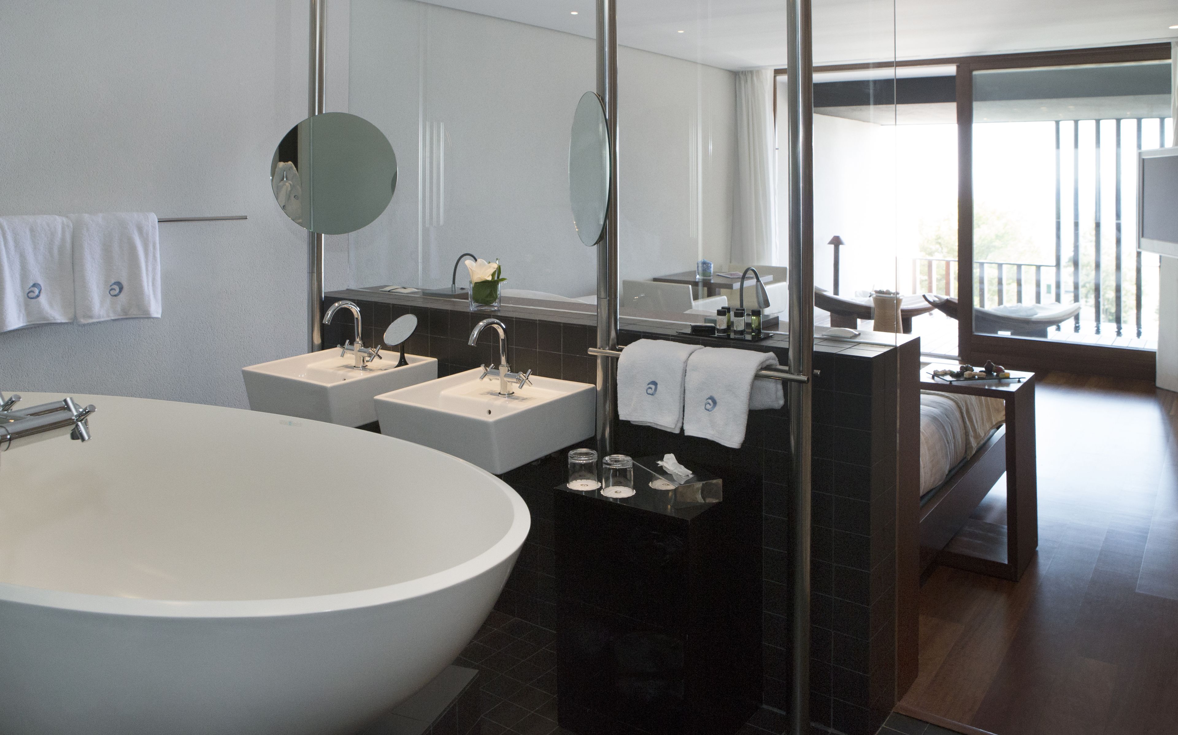 Een moderne badkamer met een ruime badkuip, twee wastafels, een spiegel en een douche.