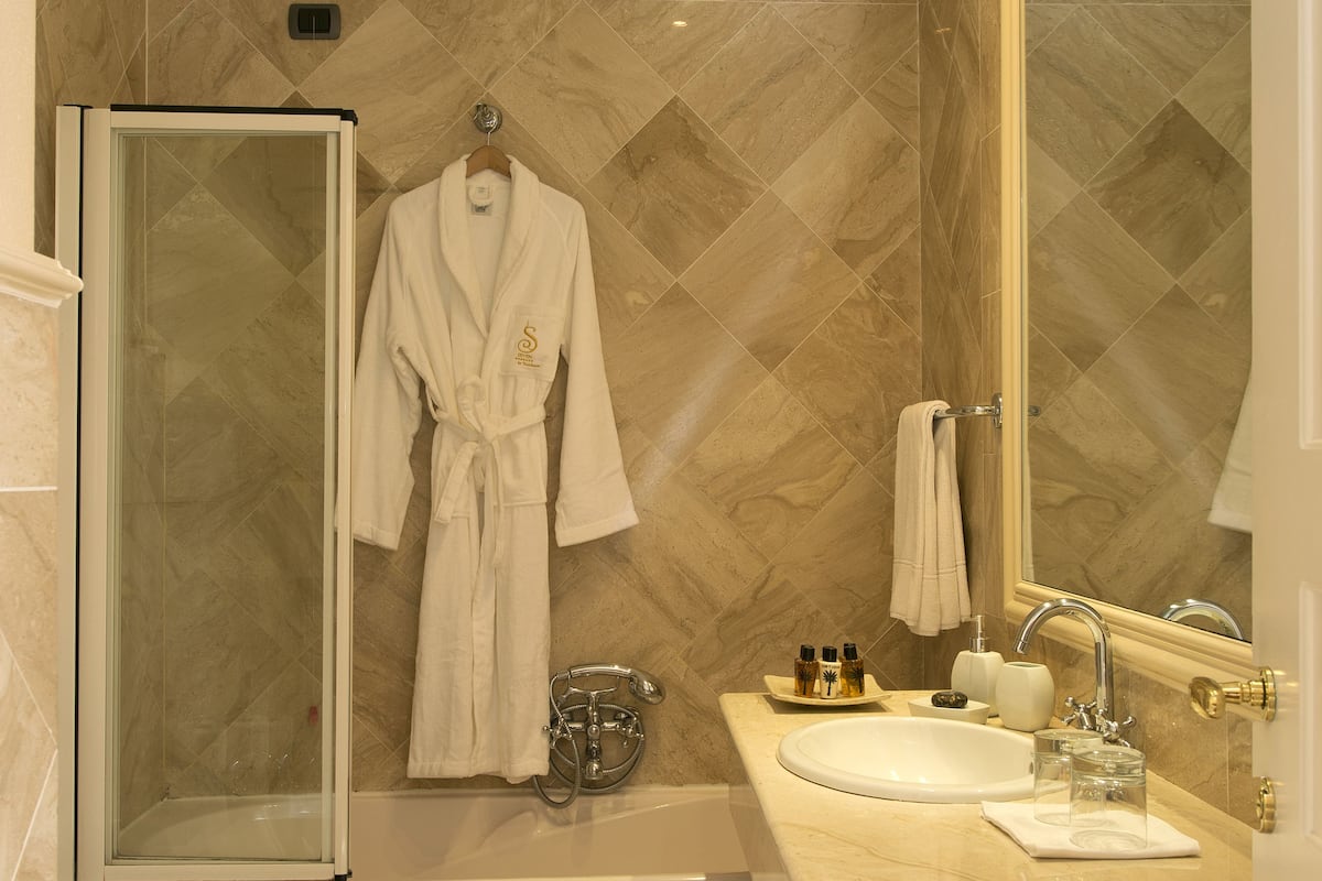 Un bagno con una vasca, una cabina doccia in vetro, un water e un lavabo con specchio.