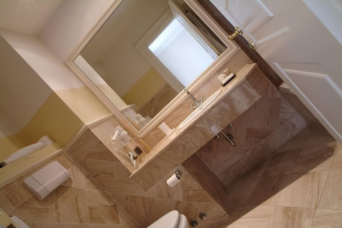 Un bagno con pavimento in marmo, lavabo con specchio e servizi igienici.
