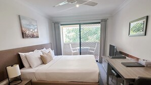 Habitación de hotel con cama, escritorio, silla y vistas al exterior.