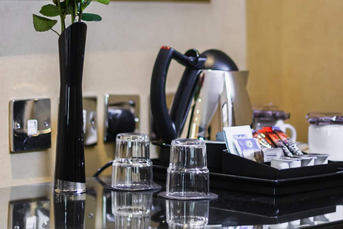 Une chambre d’hôtel avec un vase de roses rouges sur une table, un téléphone et un plateau contenant divers objets.