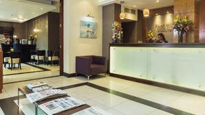 Uma área de recepção de hotel com design moderno, com balcão de recepção, espaço para sentar e um bar.