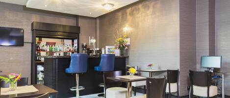 A modern bar area with a counter, bar stools, and a television.
