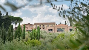Un immeuble à plusieurs étages, doté d’un toit plat, entouré d’une végétation luxuriante et surplombant un ciel dégagé.