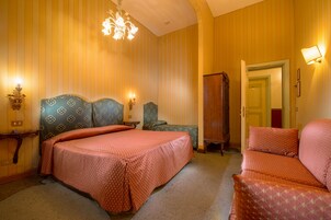 Hotellihuone, jossa on suuri sänky, sohva, tuoli ja vaatekaappi.