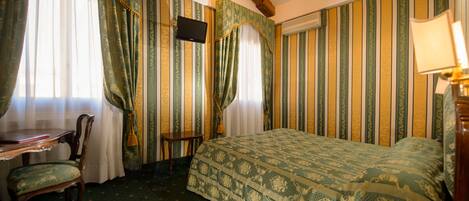 Una habitación de hotel con cama, escritorio, silla y televisor.