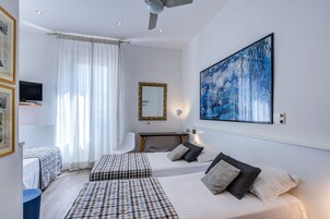 Una camera d'albergo con due letti, una scrivania, una sedia, una televisione, un quadro di grandi dimensioni e una ventola a soffitto.