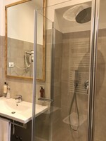 Un bagno moderno con doccia vetrata, lavandino con specchio e articoli da toilette.