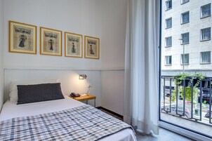 Een hotelkamer met een bed, nachtkastje, telefoon en ingekaderde foto's aan de muur.
