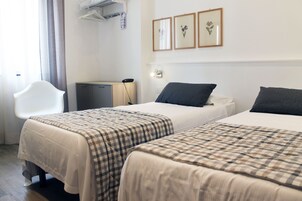 Ένα δωμάτιο ξενοδοχείου με δύο κρεβάτια, ένα γραφείο, μια καρέκλα και ένα μικρό ντουλάπι.