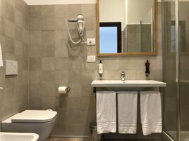 Een moderne badkamer met toilet, bidet en een douchecabine met glazen wanden.