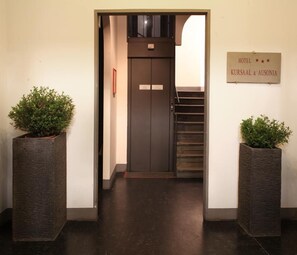 A hotel entrance with a dark door, a staircase, and two potted plants. - Kursaal and Ausonia Hotel (Florence)