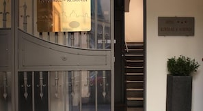 A hotel entrance with a metal gate, a sign above the gate, and a staircase leading inside. - Kursaal and Ausonia Hotel (Florence)