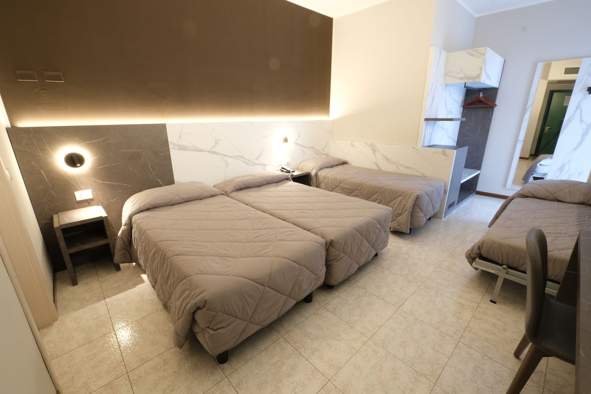 A modern hotel room with two beds, a small bedside table, and a built-in wardrobe.