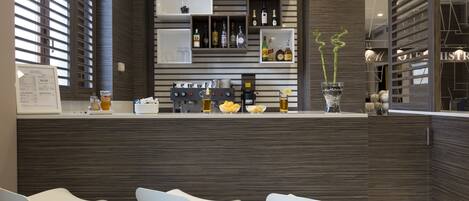 A modern kitchen with a bar area, featuring a counter with bar stools, wooden cabinets, and a wine rack.