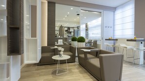Uma sala de estar moderna com um sofá, uma mesa de centro e uma área de cozinha visível através de uma porta aberta.