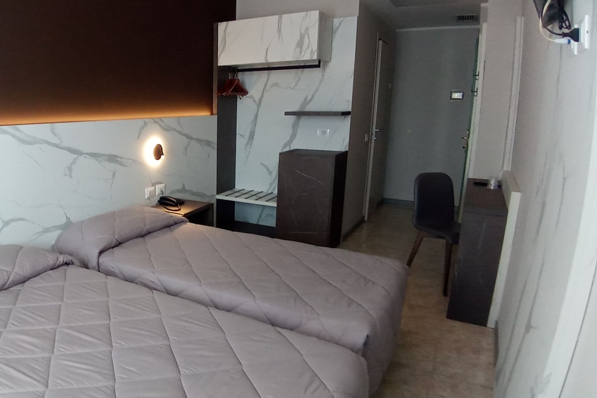 A modern bedroom with a bed, bedside lamps, a mirror, and a desk.