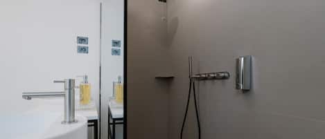 A modern bathroom with a shower, a sink, and a toilet.
